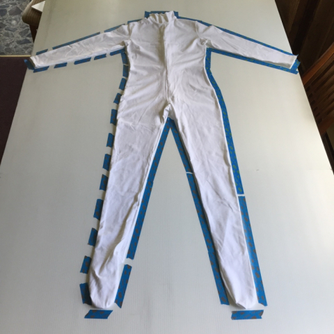 Taped around the perimeter.  I will mark and cut about 1"-2" wider so that the unitard will stretch flat onto it.
